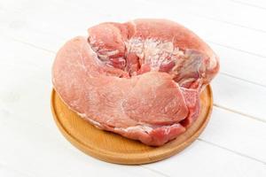 frisches Schweinefleisch auf einem Schneidebrett zum Kochen bereit. Schweinefleisch auf weißem Holzhintergrund foto