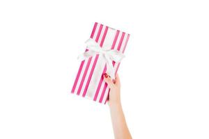 frauenhände geben eingewickeltes weihnachts- oder anderes handgemachtes geschenk in rosa papier mit weißem band. isoliert auf weißem Hintergrund, Ansicht von oben. Thanksgiving-Geschenkbox-Konzept foto