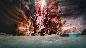 Weiblicher Touristenspaziergang im Wasser in der berühmten Flussschlucht von Wadi Mujib in erstaunlichen goldenen Lichtfarben. Wadi Mujib Reiseziel in Jordanien foto