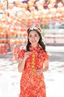 vertikales Bild. frohes chinesisches neujahr. eine junge dame, die traditionelles cheongsam qipao kleid trägt, das segensvermögenskarte im chinesischen buddhistischen tempel hält. chinesischer text bedeutet gesegnet von einem glücksstern. foto