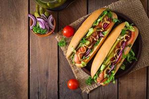 Hot Dog mit Gurken, Tomaten und Salat auf Holzhintergrund foto