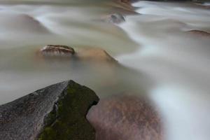 Dies ist ein schönes Foto eines Wasserstroms, der in einem Fluss im Dorfgebiet fließt.