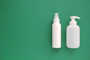 weiße Kunststoffspenderpumpe ohne Markenzeichen und Sprühflasche auf grünem Hintergrund mit Kopierraum. kosmetikverpackungsmodell, flüssiger seifenflakon, händedesinfektionsmittel ohne etikett, shampoo bio spa, duschgel foto