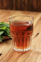 warmer tee in einem glas, mit frischem teeblatthintergrund foto