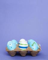 Ostern bunte handgefertigte bemalte blaue Eier in einer Schachtel auf violettem Hintergrund foto