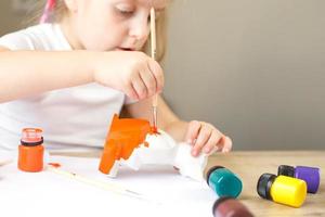 Ein kleines Mädchen malt einen Spielzeugfuchs aus Ton. DIY-Konzept foto