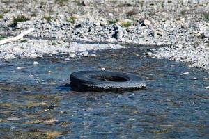 verlassener Reifen in einem Fluss foto