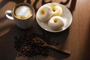 Hot Latte und Donuts auf Holztisch hinter Fenster foto