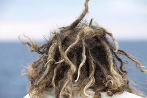 Rasta-Mannhaar im Wind, der den Ozean betrachtet foto