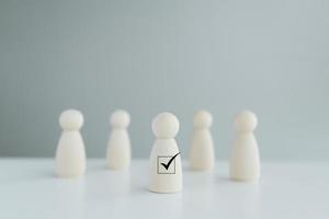 hölzerne Personenfigur, die vor der Menge steht, mit Häkchen für die Wahl der Führung. Mitarbeiterführer oder Freiwilliger. Einstellung von Unternehmen und Personalauswahl. Personalmanagement. foto