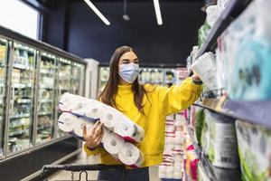 toilettenpapiermangel.frau mit hygienemaske kauft toilettenpapiervorräte aufgrund von panikkäufen und produkthorten während des ausbruchs der virusepidemie.mangel an hygieneprodukten stockfoto foto