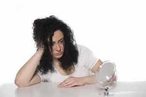 Haarprobleme. junge Frau, die ihre beschädigten und gespaltenen Haare überprüft foto