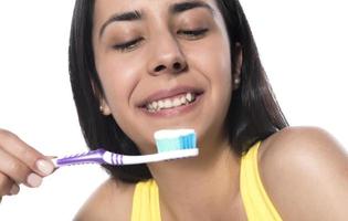 glückliche junge Frau mit gesunden Zähnen, die eine Zahnbürste hält foto