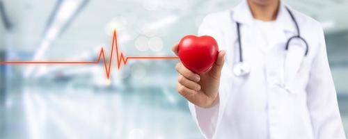 Nahaufnahme der Hand des Arztes, der ein rotes Herz für Herzkrankheiten hält Krankenhauszimmer für Krankenversicherungsdienstleistungskonzept