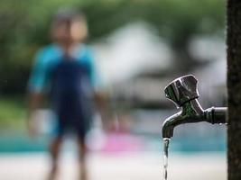 Nahaufnahme des tropfenden Wasserhahns am Swimmingpool foto