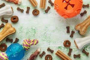 eine schüssel mit hundefutter, hundeleckereien und spielzeug auf einem holzboden. foto