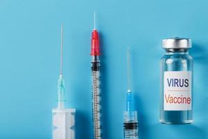 spritzen und ampulle mit dem impfstoff gegen das virus von krankheiten auf blauem hintergrund.