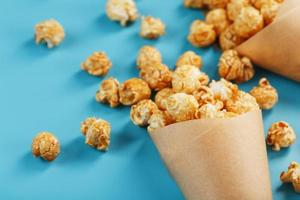 Karamell-Popcorn in einem Papierumschlag auf blauem Hintergrund. foto