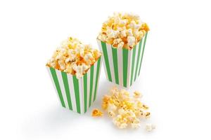 Zwei grün-weiß gestreifte Kartoneimer mit leckerem Käse-Popcorn, isoliert auf weißem Hintergrund foto