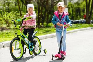 glückliche Freundin fährt Roller und Fahrrad im Schlepptau und lacht glücklich foto