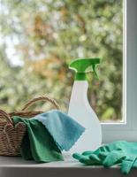 Putzmittel, Tücher und Gummihandschuhe in einem Körbchen auf der Fensterbank. Allgemeines Reinigungskonzept foto
