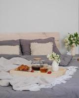 Frühstück im Bett. Tablett mit Tee, Croissant und Erdbeeren auf dem Bett im Schlafzimmer foto