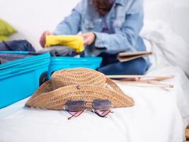 frau, die kleidung von persönlichen geräten sammelt, bereitet sich darauf vor, gepäck für einen erholsamen urlaub zu verstauen. foto