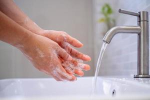 Waschen Sie Ihre Hände mit Seife, verhindern Sie Viren und Bakterien im Wasserhahn mit fließendem Wasser. gute Hygiene vor dem Essen oder dem Umgang mit öffentlichen Gegenständen foto