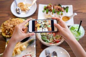 frau, die eine mobile kamera benutzt, um bilder von essen zu machen, die auf dem tisch im haus platziert werden. nach dem Anruf, um Essen online von zu Hause aus zu bestellen. Bleiben Sie zu Hause und kaufen Sie während der Ausbreitung des Covid-19-Virus online ein. foto