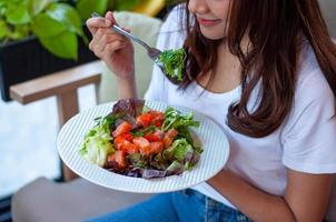 Junge Frauen, die abnehmen wollen, essen für die Gesundheit einen Lachs-Gemüse-Salat. Frauen, die sich für ein gesundes Ernährungskonzept entscheiden foto