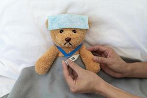 Teddybär und Bandage mit Thermometer. Krankheits- und Verletzungskonzept foto