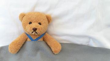 Ein trauriger Teddybär liegt krank im Bett mit Enttäuschung und Entmutigung foto