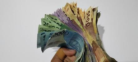 verschiedene farben und stückelungen der indonesischen rupiah-währung in der hand isolierter weißer hintergrund foto