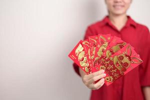 frau, die chinesischen roten umschlag mit goldenem kaninchen und segnungswort, geldgeschenk für glücklichen mondneujahrsfeiertag hält. Chinesischer Satz bedeutet Glück, gesund, glücklich und wohlhabend foto