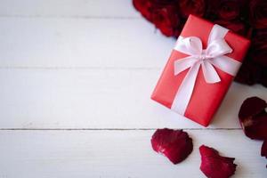Schließen Sie herauf rote Geschenkbox mit Strauß rosiger Rosen unscharfer Hintergrund. valentinstag, hochzeit, geburtstag und konzept für besondere anlässe. Platz für Text kopieren. foto
