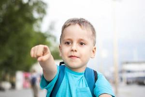 ein Junge in einem blauen T-Shirt mit einem Rucksack auf dem Rücken. Reise. Das Gesicht drückt natürliche freudige Emotionen aus. nicht inszenierte Fotos aus der Natur