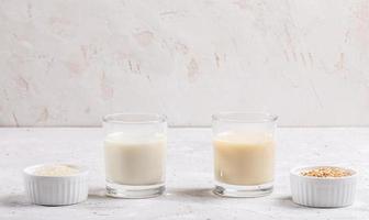 Gläser mit gesunder Reis- und Hafermilch, Schalen mit Reissamen und Haferflocken auf weißem Hintergrund. foto