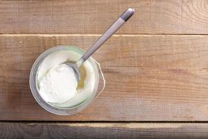 Weißer Joghurt im Plastikbecher auf rustikalem Holztisch. foto