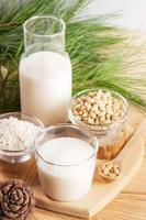 Zedernnussprodukte Milch in Glas und Flasche, Nüsse und Pulver auf Holztisch. selektiver Fokus. foto