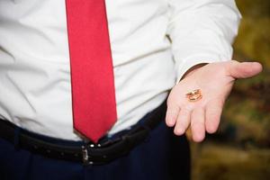 Bräutigam hält den Ehering an der Hand foto