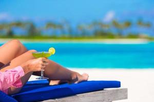 Nahaufnahme einer Person, die einen Cocktail am Strand hält foto