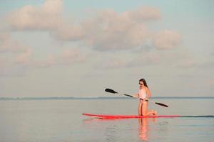 Frau auf einem Paddleboard bei Sonnenuntergang