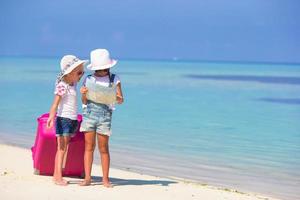 zwei Mädchen mit Karte und Gepäck am Strand foto