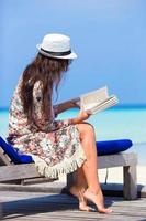 Frau, die ein Buch während eines Strandurlaubs liest foto