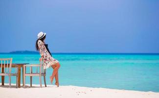 Frau, die sich auf einen Stuhl am Strand stützt foto