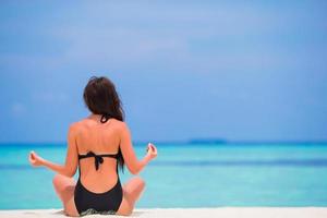 Frau meditiert an einem weißen Strand foto