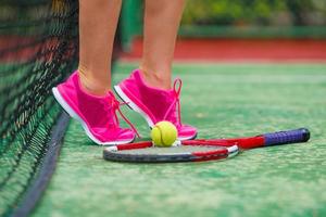 Nahaufnahme von Turnschuhen in der Nähe des Tennisschlägers und des Balls foto