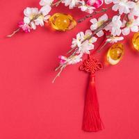 Designkonzept des chinesischen neuen Mondjahres - schöner chinesischer Knoten mit Pflaumenblüte isoliert auf rotem Hintergrund, flache Lage, Draufsicht, Overhead-Layout. foto