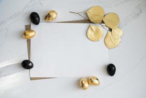 modell, goldene und schwarze ostereier mit goldenen eukalyptusblättern. foto