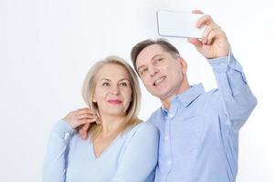 glückliches paar, das selfie mit dem smartphone lokalisiert auf weiß nimmt foto